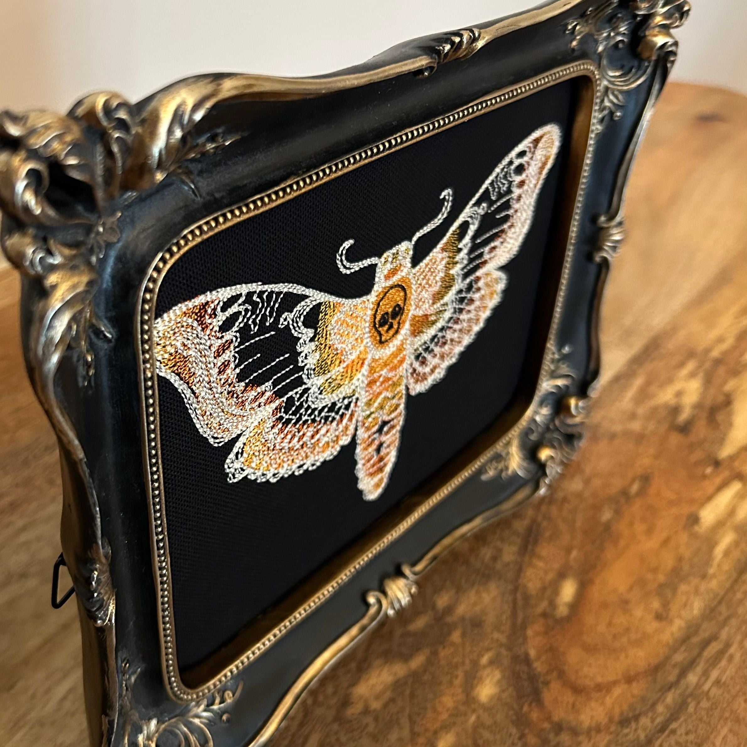 Death Head Moth lace embroidery art framed in a distressed gold and black vintage gothic picture frame.