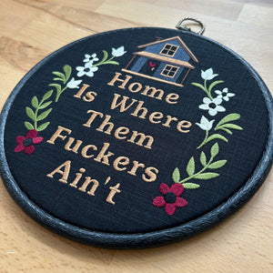 Funny embroidered hoop wall art with floral design and cozy house, featuring a humorous quote about home and peace. Handmade rustic gift for modern farmhouse or quirky decor.